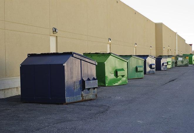 a construction worker empties a wheelbarrow of waste into the dumpster in Anson